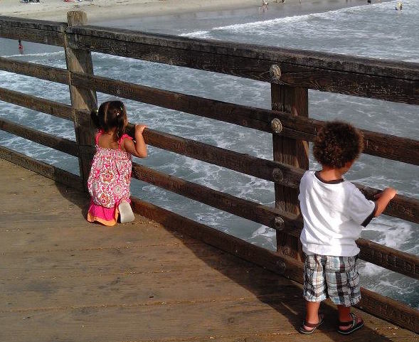 kids looking at the waves on the pier